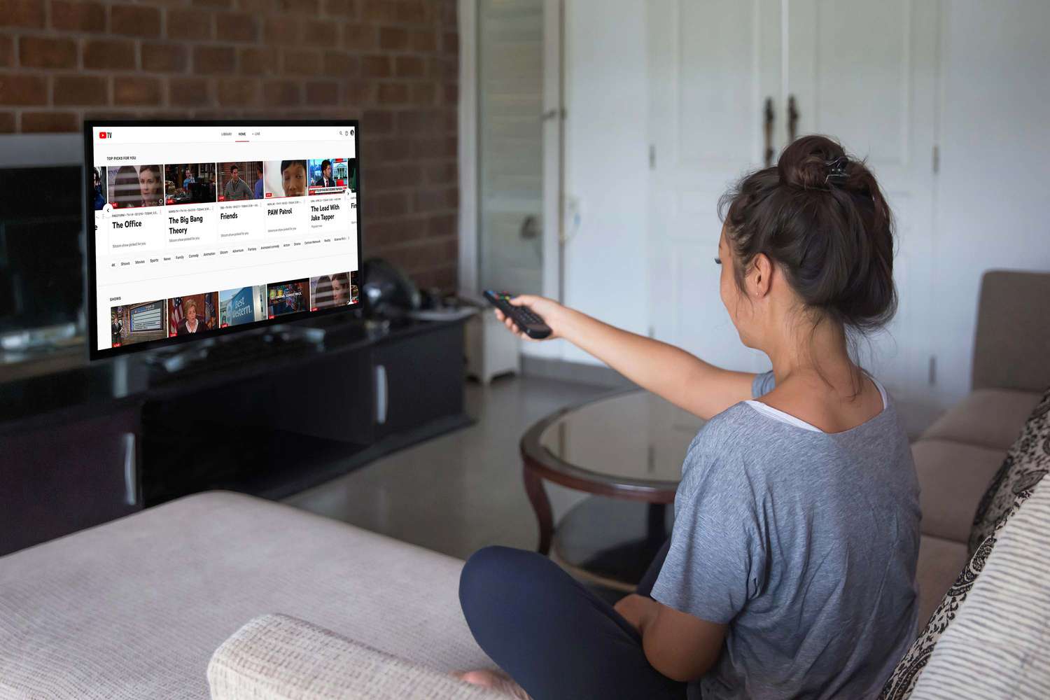 A woman watches YouTube TV on her television.