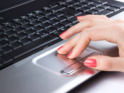 A hand using a Windows 10 laptop's trackpad.