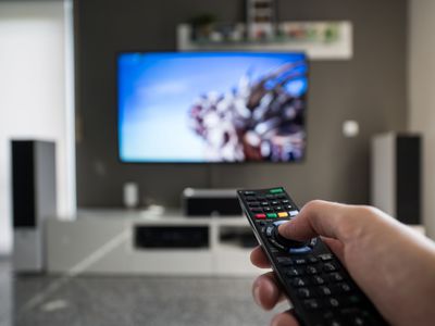 Man pressing remote pointed at TV