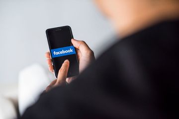 An image of a man looking at Facebook on a smartphone.