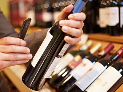 A man scanning a wine bottle with an app on his smartphone.