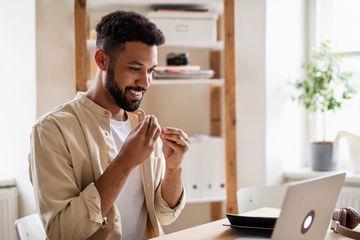 Man using sign language on a video call via a laptop