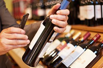 A man scanning a wine bottle with an app on his smartphone.