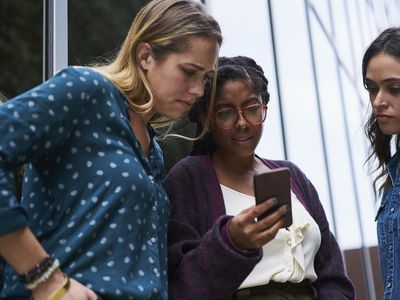 Businesswoman looking at phone outside office.