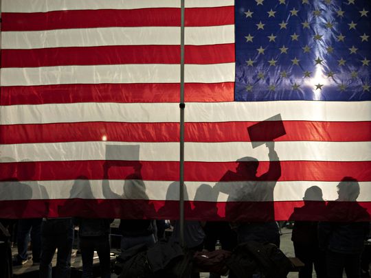 People Silhouetted Against An American Flag.