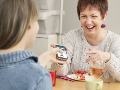 A mother hands her child a phone after setting Amazon parental controls.