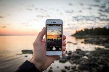 A person holding an iPhone taking a picture of the beach