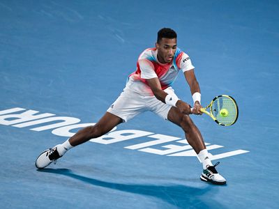 Felix Auger-Aliassime of Canada hits a backhand against Daniil Medvedev of Russia during day 10 of the 2022 Australian Open at Melbourne Park on January 26, 2022 in Melbourne, Australia.