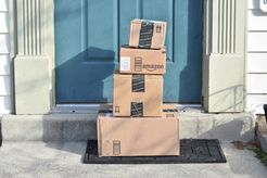 Tower of Amazon packages at blue house door