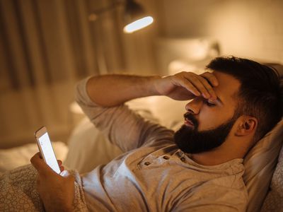 Worried man in bed reading phone