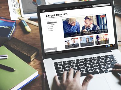 An image of a man looking at a news site on a laptop.