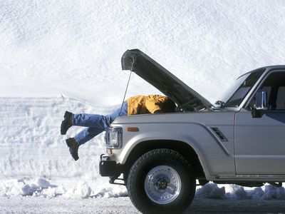 Man removing a car battery in the dead of winter