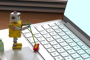 Tiny robot with mop and cleaner pretending to clean a laptop.