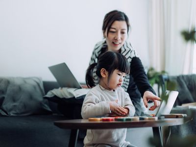 A child looks at her mother pointing at something on an iPad