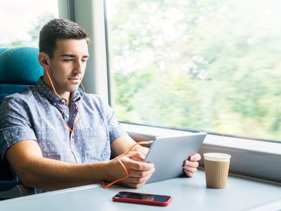 Man with tablet and headphones on train