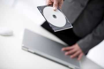 Person holding a CD and laptop.