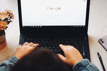 Someone with knuckle tattoos using Google Chrome on a black laptop