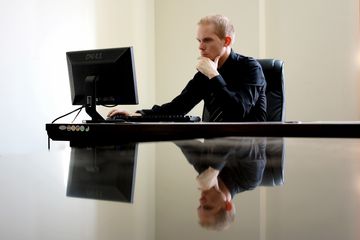 Man working at computer keyboard on reflective desk