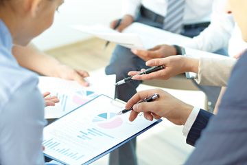 Group of colleagues discussing spreadsheet information at a meeting