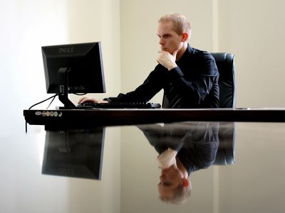 Man working at computer keyboard on reflective desk