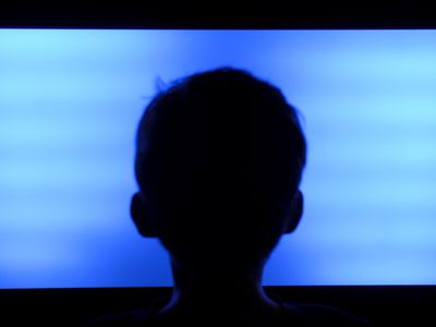 Silhouette of a child's head in front of a flat screen TV