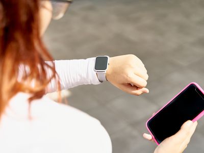 A woman holding an iPhone and looking at her Apple Watch