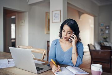 A customer support rep using a mobile phone while sitting at a table.