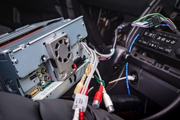 Head unit of a car stereo pulled out of the housing unit inside of a car