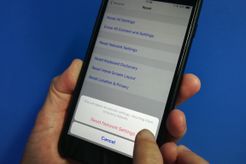 A finger about to tap "Reset Network Settings" confirmation on iPhone