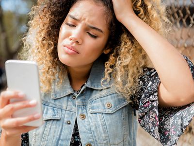 A person is looking frustrated while using a smartphone.