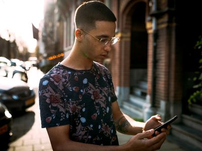 A young male adult with glasses holding an Android smartphone.