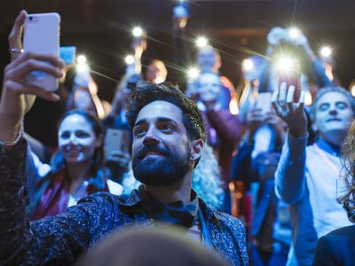 Crowd of concert goers using the flashlight on their phones