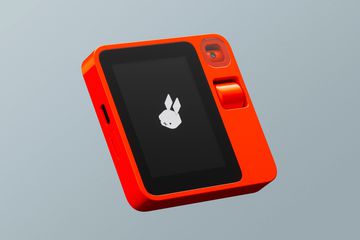 The Rabbit R1 AI device in red against a gray background.