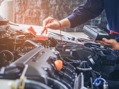 A car mechanic diagnosing a car engine.