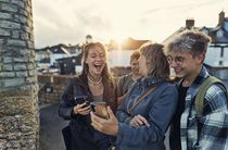 A group of people looking at their phones and laughing on a street in the UK.