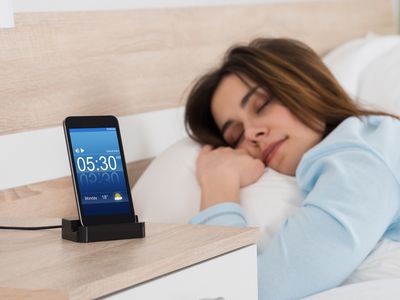 A sleeping woman with a phone showing the time next to her