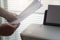 Man collecting papers at printer