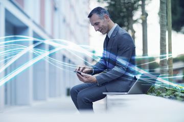 Businessman sitting outside working on an iPhone