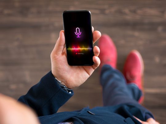 A man holding his iPhone while recording a phone call.