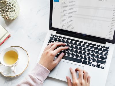 Computer with Outlook search function on the screen. tea and notebook in table