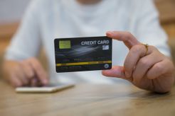 Hand holding credit card next to a smartphone