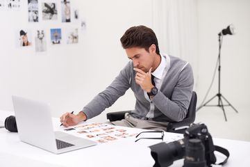 Photographer in studio working on images at laptop