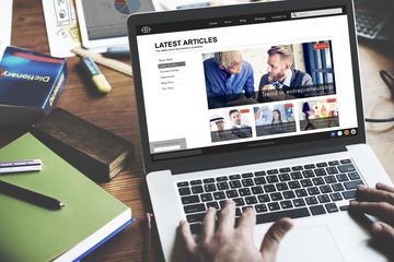 An image of a man looking at a news site on a laptop.