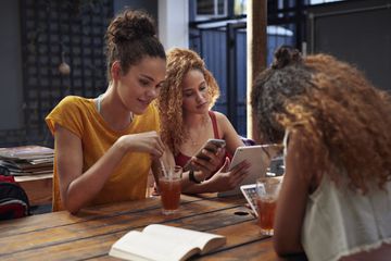 Teenagers using apps on smartphones and tablets.