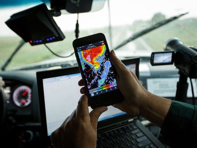 A storm chaser uses a radar app on his phone.