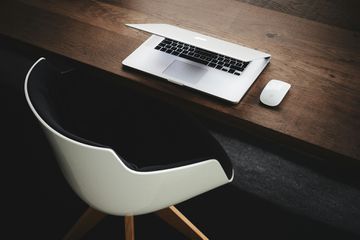 MacBook on a table next to a chair