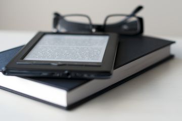 E-Reader and book with reading glasses