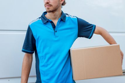 A delivery man wearing a blue shirt delivering an Amazon Prime package.