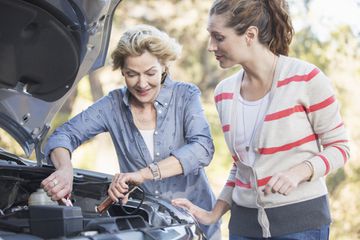 Two women jumpstarting a car battery