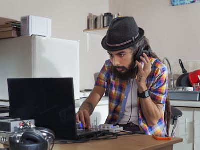 Man at table using computer to edit music.